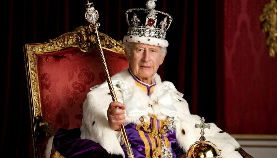 Kong Charles sidder her med The Imperial State Crown på hovedet iført The Robe of Estate mens han holder The Sovereign's Orb.
