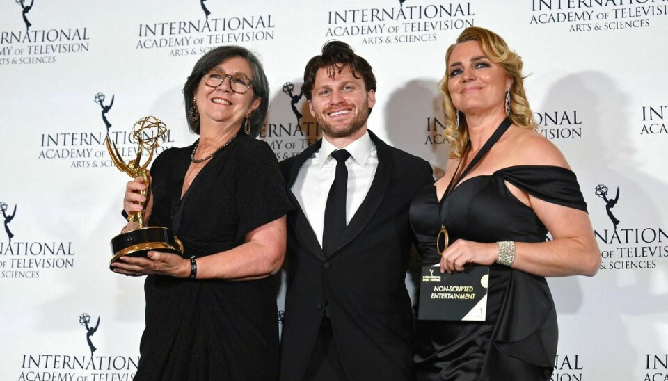 Karin Holden og Jenni Wilks poserer med den statuette, som de natten til tirsdag vandt for serien 'Love on the Spectrum' ved International Emmy Awards i New York. Mellem dem ses skuespiller Jon Rudnitsky.