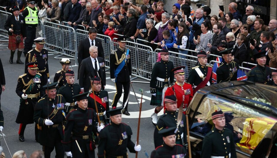 Dronning Elizabeths kiste er svøbt i det royale rødgule skotske flag. Oven på kisten bag i bårevognen ligger en krans med blomster fra Balmoral-slottet, hvor dronningen tilbragte sin sidste tid. Umiddelbart bag bårevognen følger kong Charles, prinsesse Anne, prins Andrew og prins Edward.