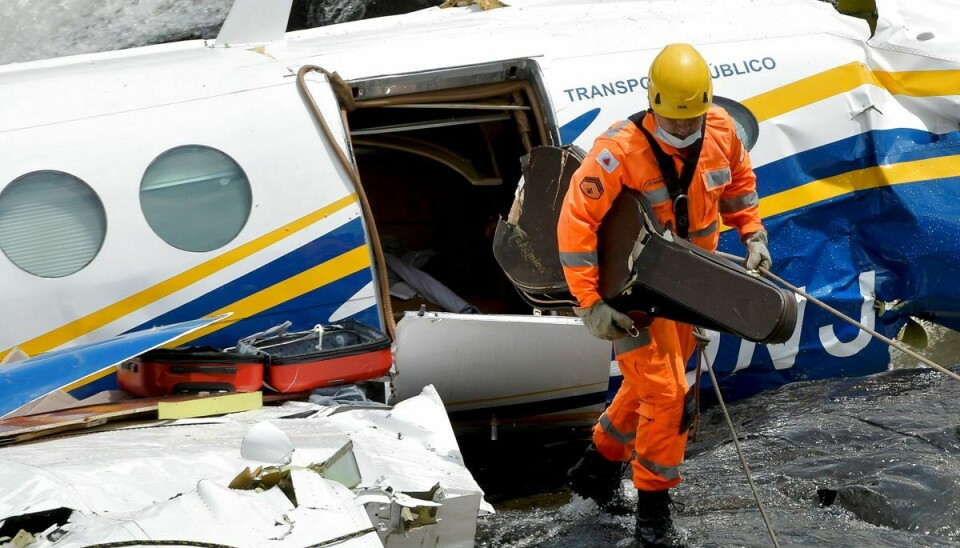 En redningsarbejder bjærger her Marília Mendoncas guitarkasse ud af flyet.