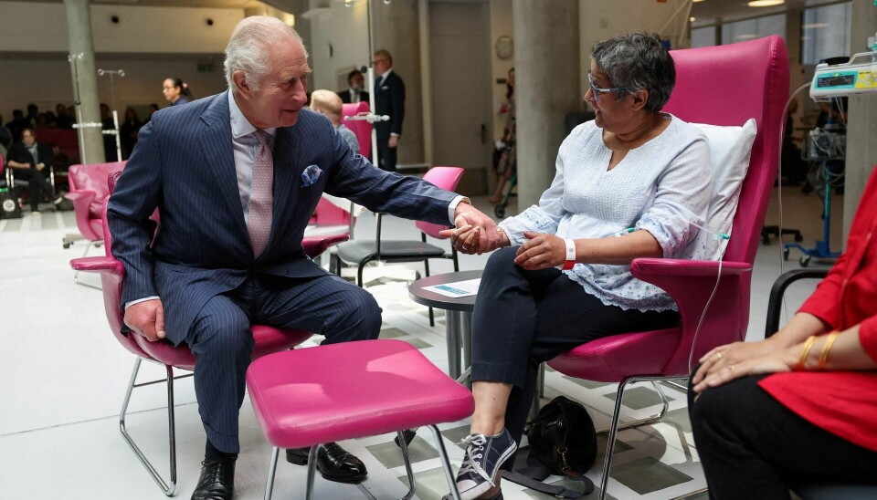 Kong Charles holder kræftpatient Asha Millan i hånden, mens han indfølende lytter til hendes personlige beretning om kræft.