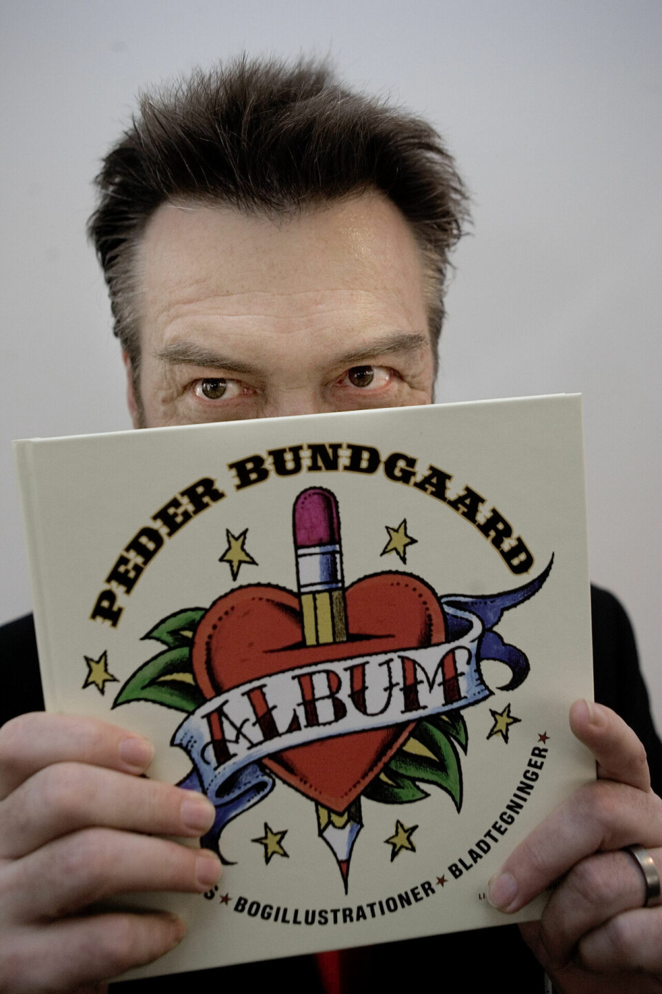 Peder Bundgaard holder forsiden af bogen 'Album' op for fotografen ved sin 60 års fødselsdagsreception.