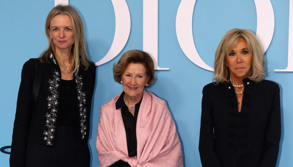 Dronning Sonja ses her flankeret af Christian Dio CEO Delphine Arnault (th) og den franske præsidentfrue ved Dior-modeshowet tirsdag i Paris.