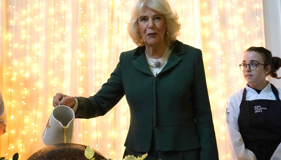 Dronning Camilla ses her overhælde den omtrent 10 kilo tunge traditionelle engelske julebudding med en betragtelig mængde brændevin.