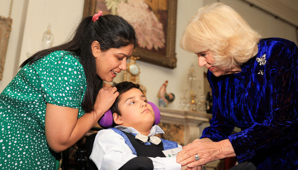 Dronning Camilla ses her hygge om en af sine unge gæster under torsdagens julearrangement i Clarence House.