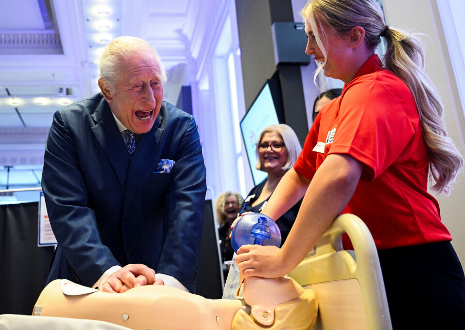 Kong Charles giver livgivende førstehjælp til en 'dummy-patient' under kyndig vejledning af 17-årige Mia Alami.