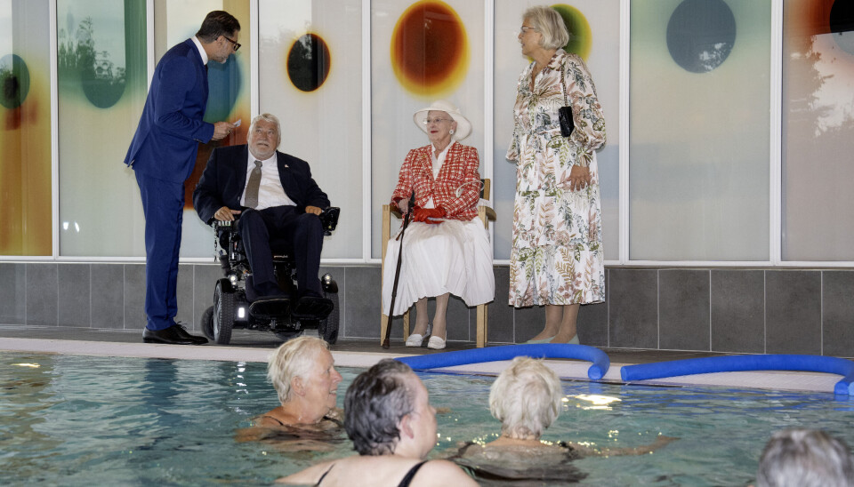 Dronning Margrethe følger med i træningen i det våde element fra bassinkanten sammen med Peter Mads Clausen.