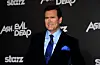 Bruce Campbell foran væg med Ash vs Evil Dead- og Starz-logoer ved premiere